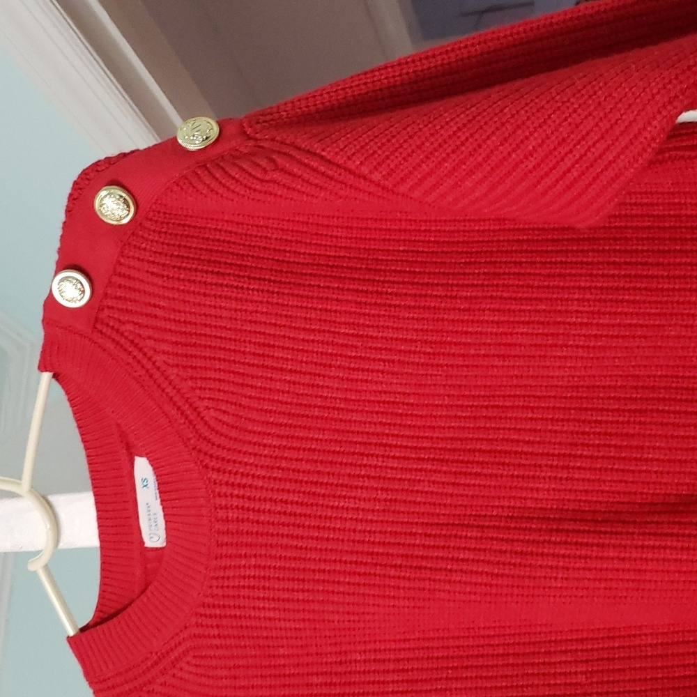 A Primark red sweater with holden buttons on the left shoulder.